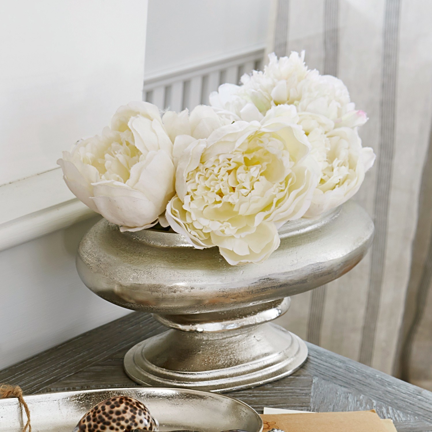 Srebrna metalowa misa dekoracyjna z białymi kwiatami na drewnianym stole do salonu