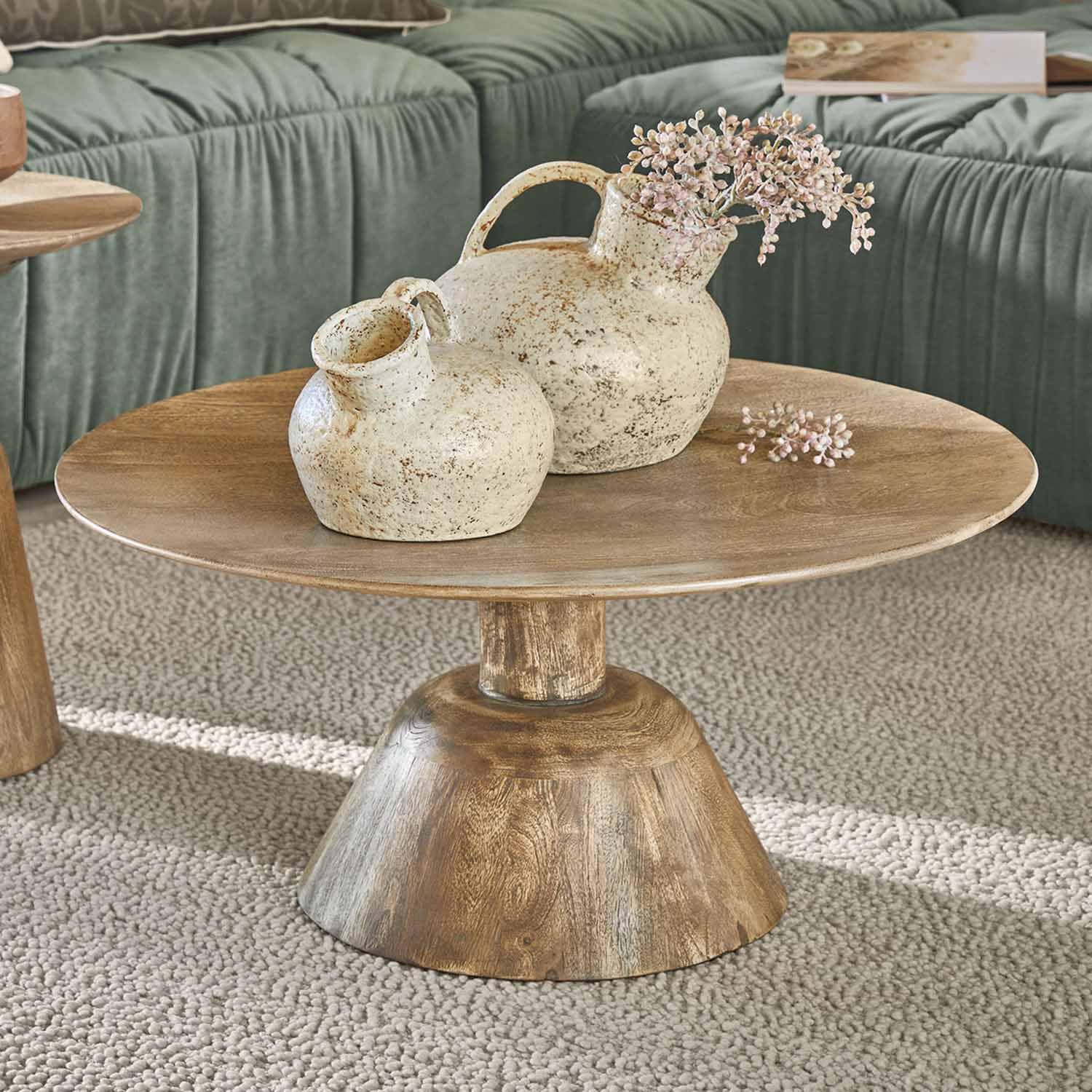 Drewniany stolik kawowy z dwoma kremowymi ceramicznymi wazonami o rustykalnym wyglądzie na dywanie