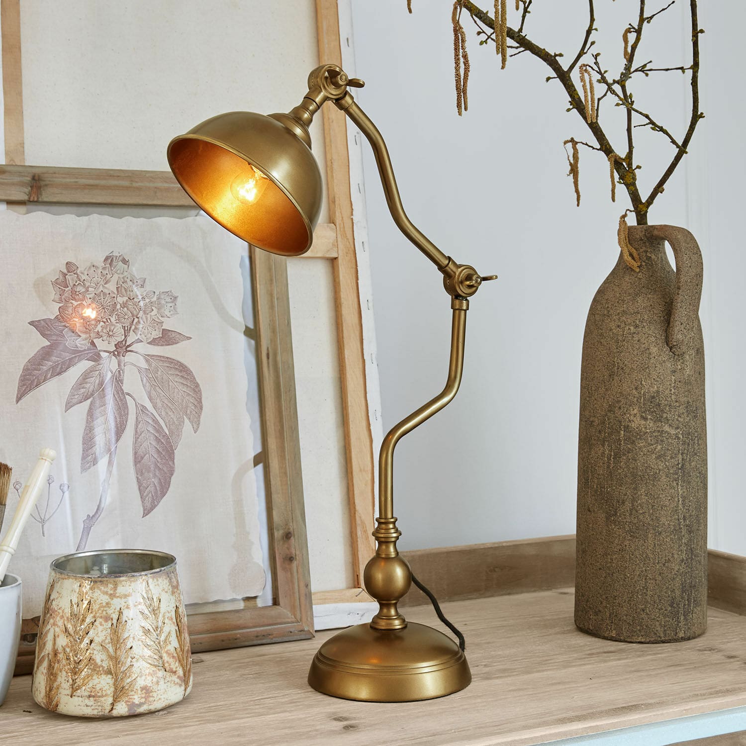 Lampa stołowa Harrowden Złota metalowa lampa stołowa z regulowanym ramieniem na drewnianym blacie z dekoracjami