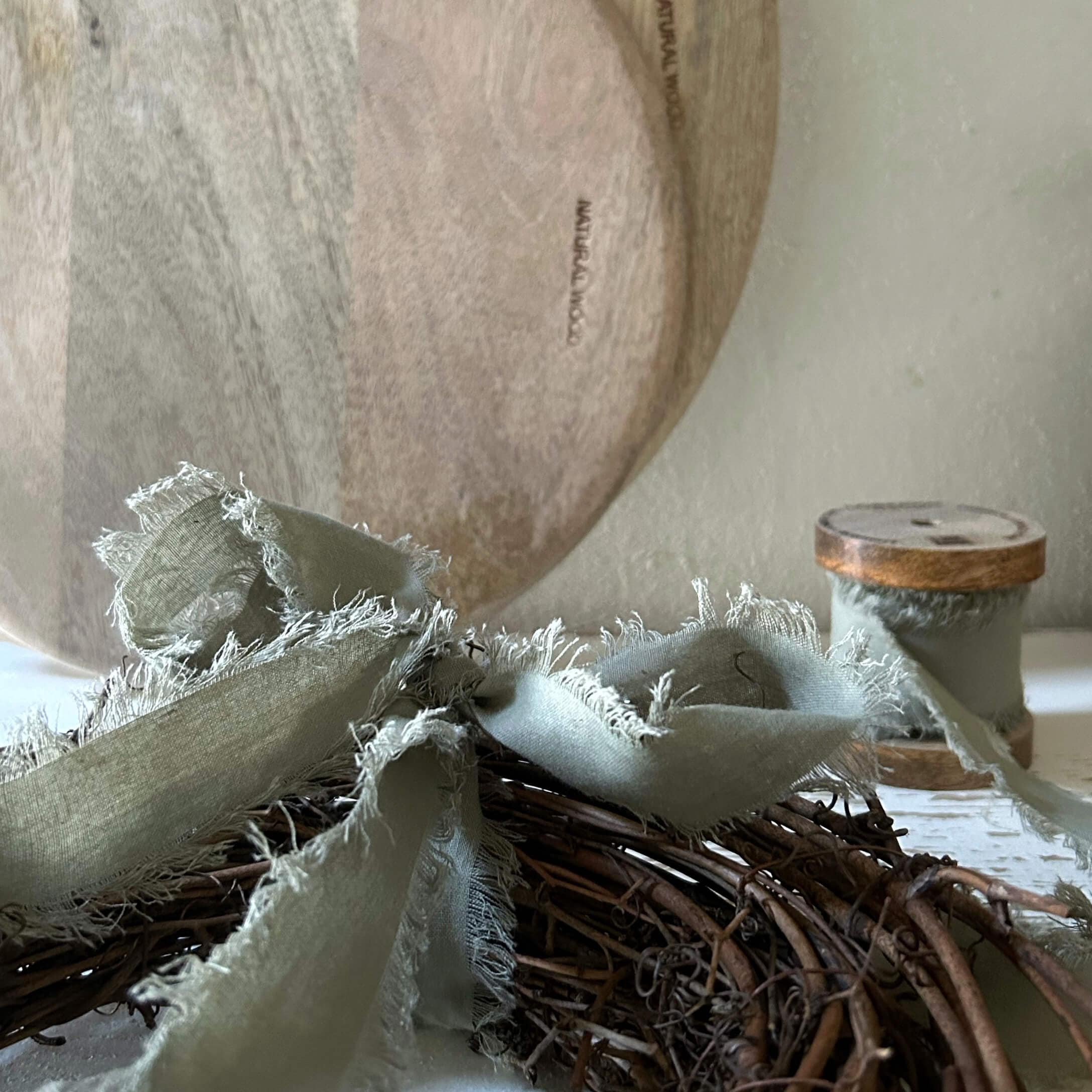 Naturalny drewniany talerz z lnianą szarą wstążką na wiklinowym wieńcu do dekoracji wnętrz