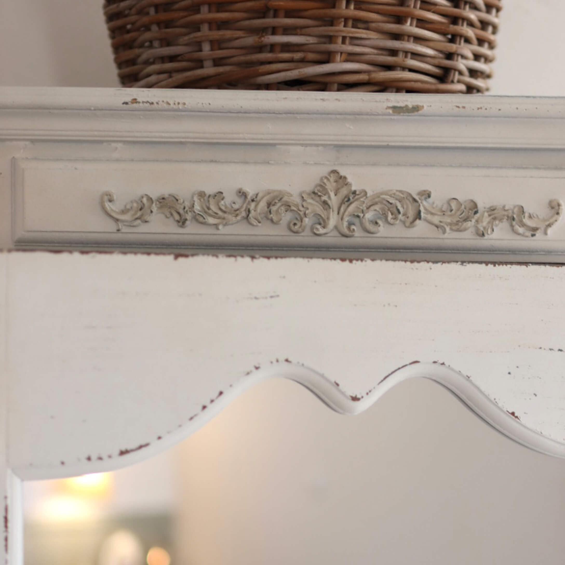 Biały drewniany mebel z ozdobnym rzeźbionym wzorem i postarzaną powierzchnią w stylu vintage