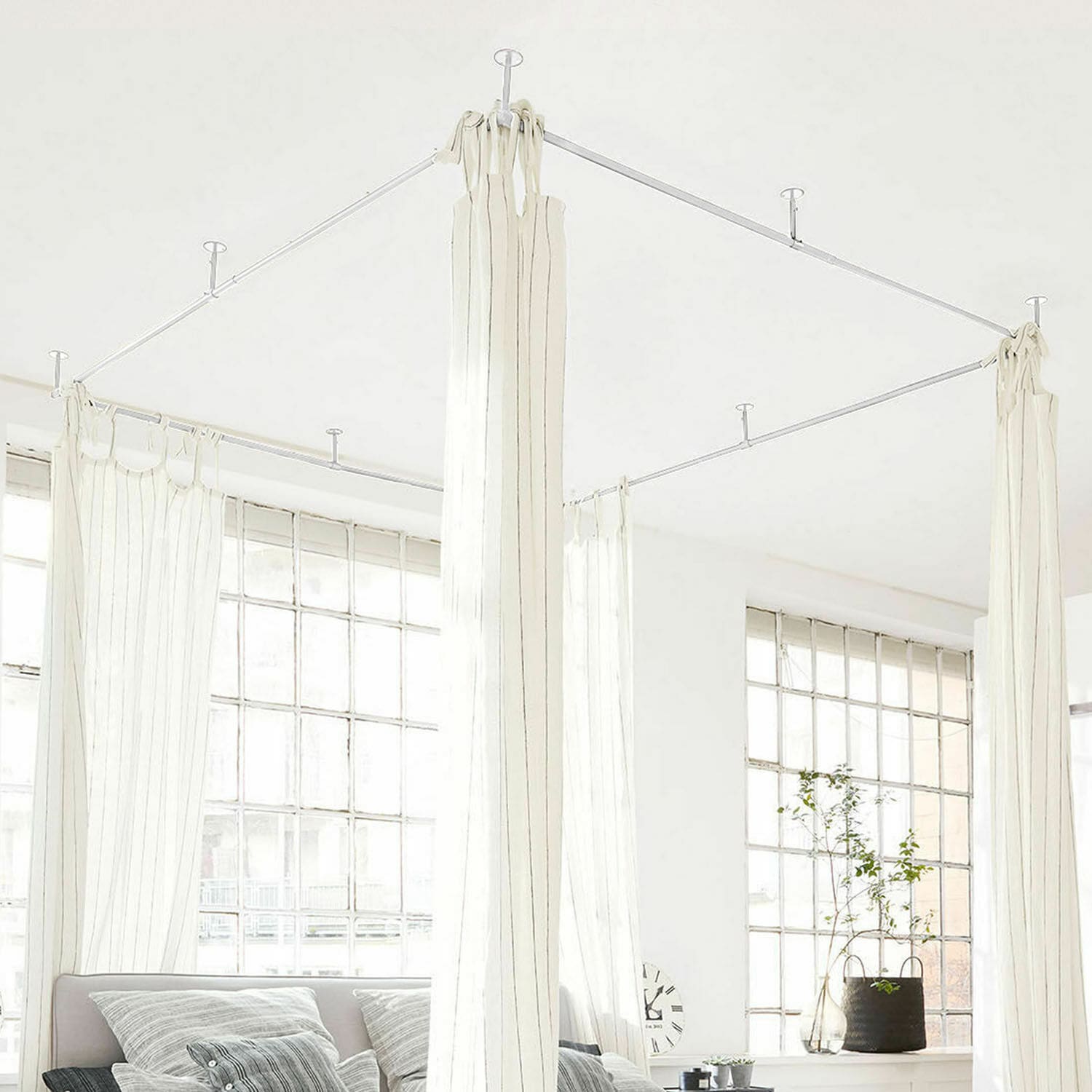 Białe zasłony z cienkimi paskami na metalowej ramie sufitowej w jasnym, nowoczesnym wnętrzu