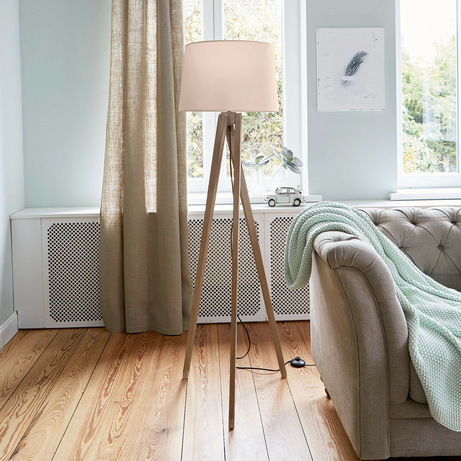 Lampa stojąca Troisième Lampa stojąca z drewnianą podstawą i kremowym abażurem w jasnym salonie z kanapą i kocem