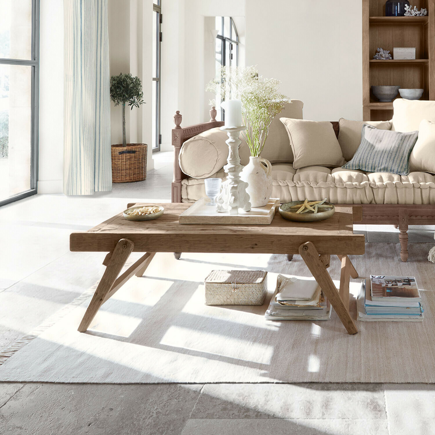 Drewniany stolik kawowy z dekoracjami na jasnym dywanie w przytulnym salonie z beżową sofą