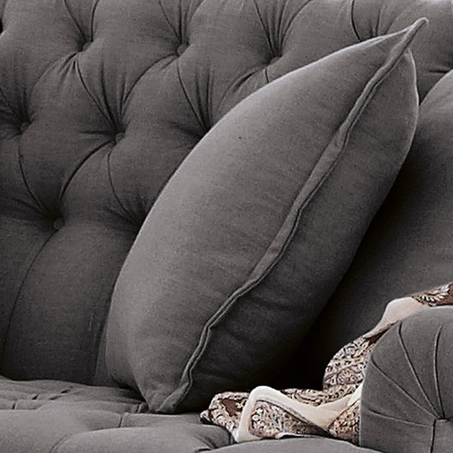 Szara pikowana sofa z miękką poduszką i dekoracyjnym wzorem na tkaninie, wygodne meble do salonu