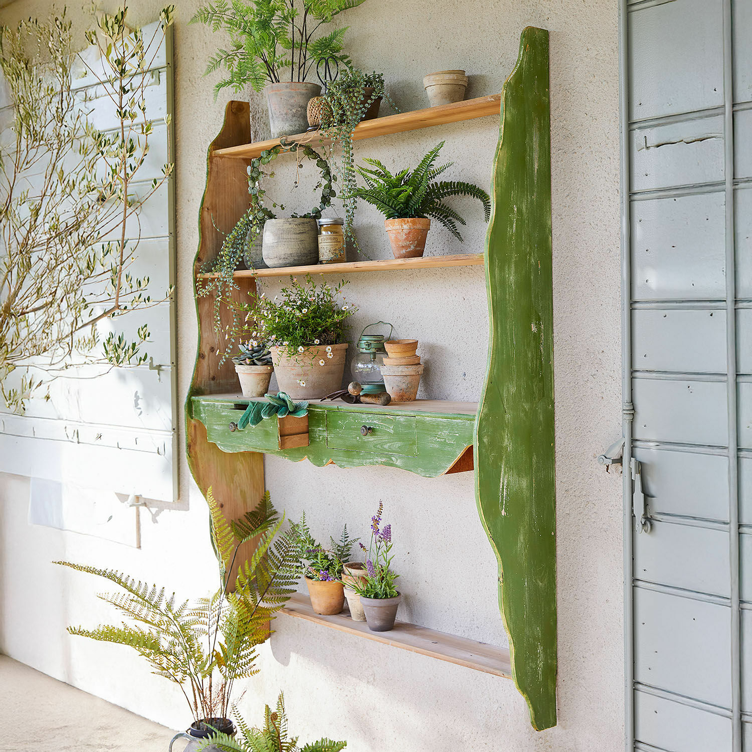 Rustykalna zielona drewniana półka ścienna z doniczkami i narzędziami ogrodniczymi do dekoracji domu