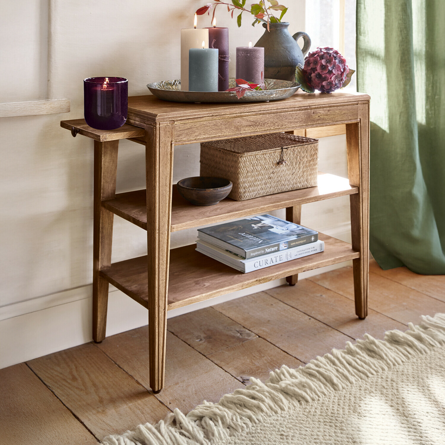 Drewniany stolik z półkami i dekoracyjnymi świecami oraz wazonem w naturalnym wnętrzu