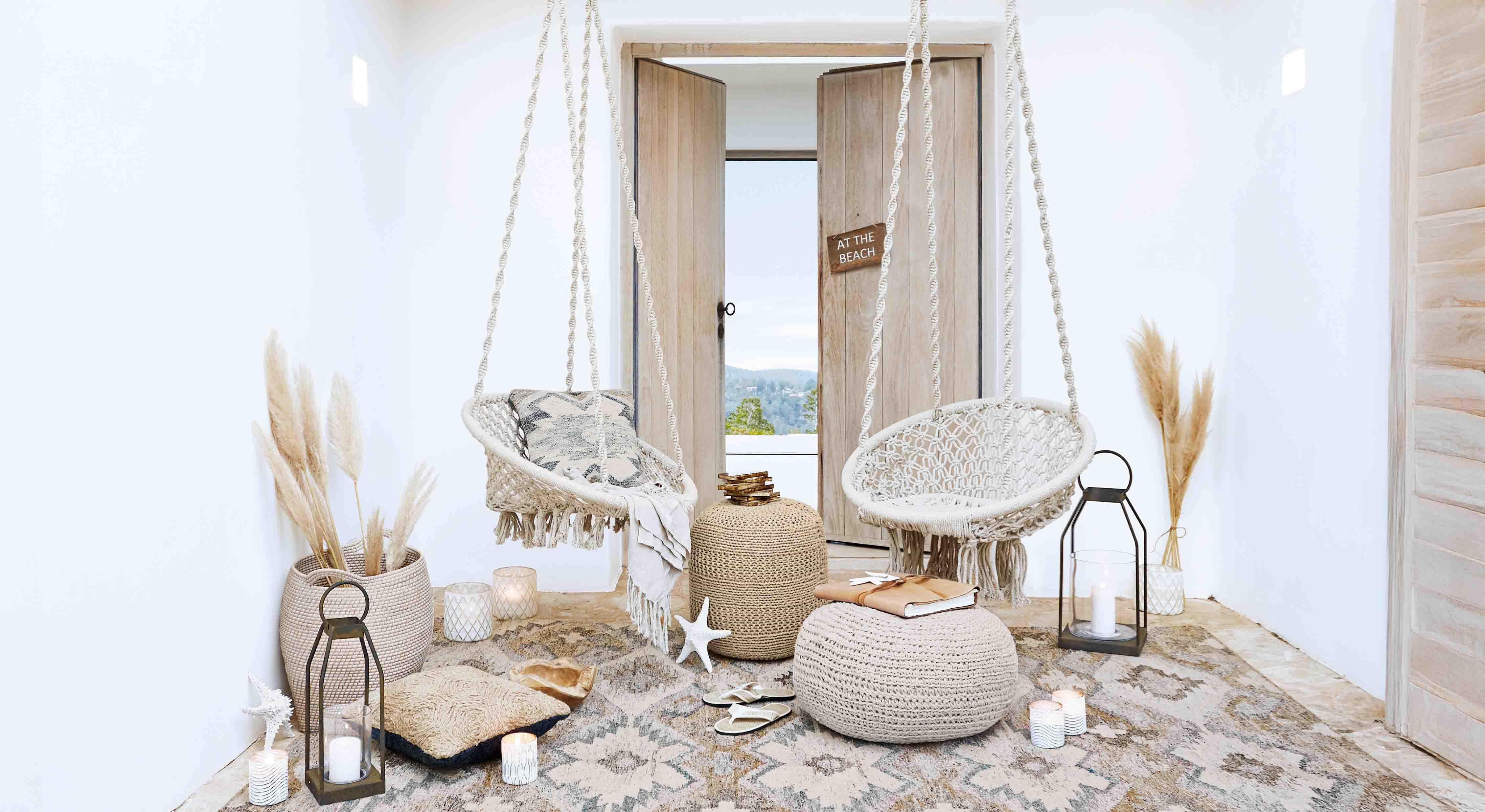 Przytulny salon z białymi wiszącymi fotelami z makramy i naturalnymi dekoracjami w stylu boho
