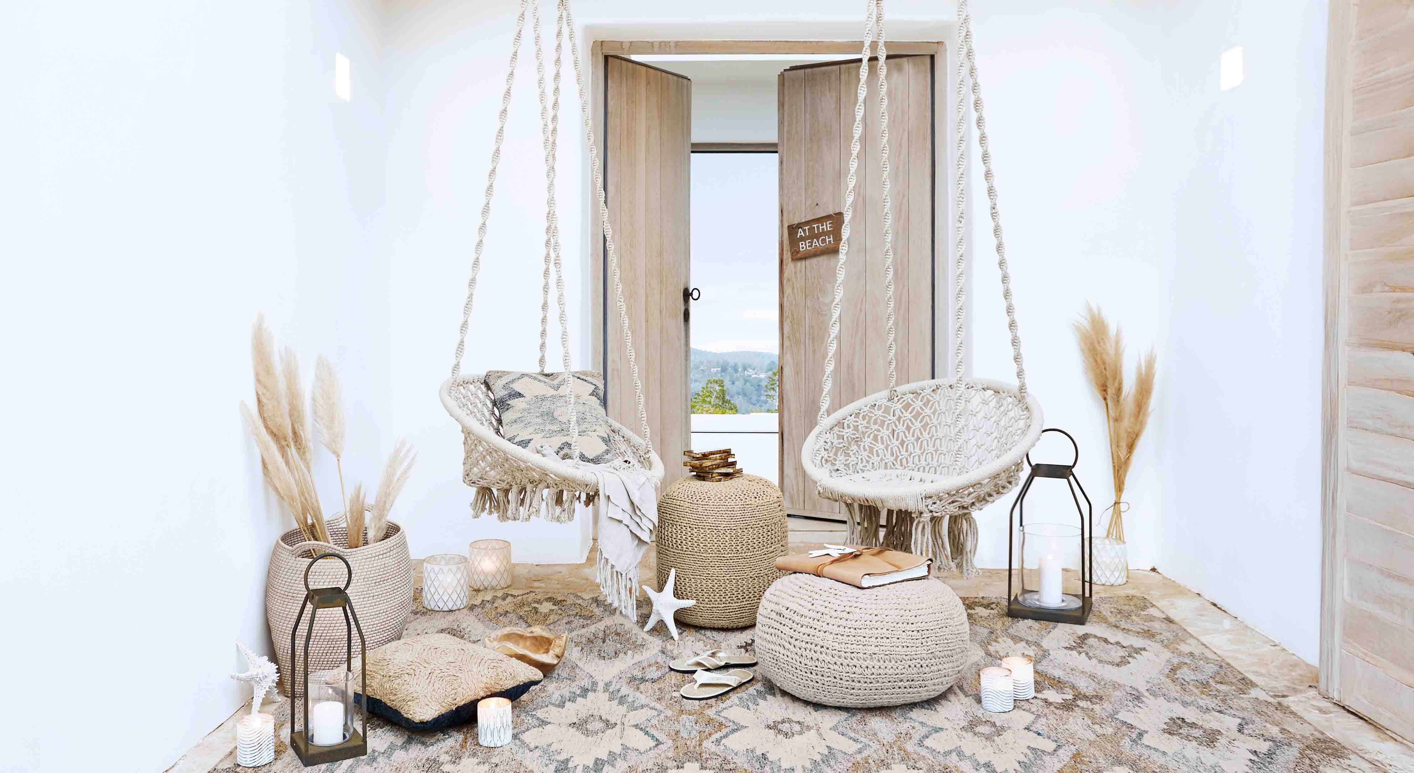 Przytulny salon z białymi wiszącymi fotelami z makramy i naturalnymi dekoracjami w stylu boho