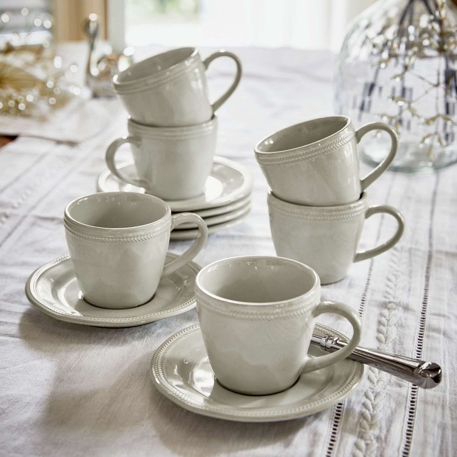 Filiżanka ze spodkiem, zestaw 6 szt. Norrvik Zestaw białych ceramicznych filiżanek z talerzykami na białym obrusie do kawy i herbaty