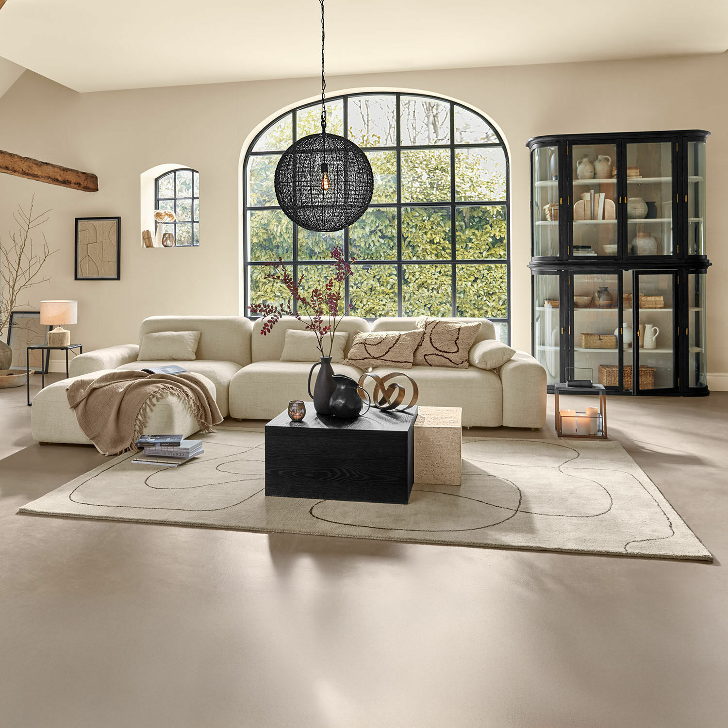 Przestronny salon z beżową sofą z tkaniny i czarną drewnianą ławą na dywanie z wzorem