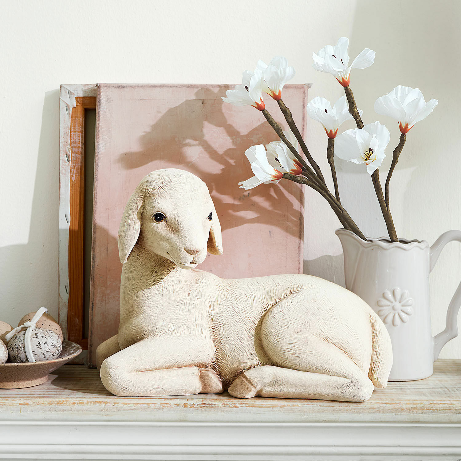 Dekoracyjny baranek Xénandrine Dekoracyjna figurka owcy w kolorze kremowym na drewnianej półce z kwiatami i jajkami