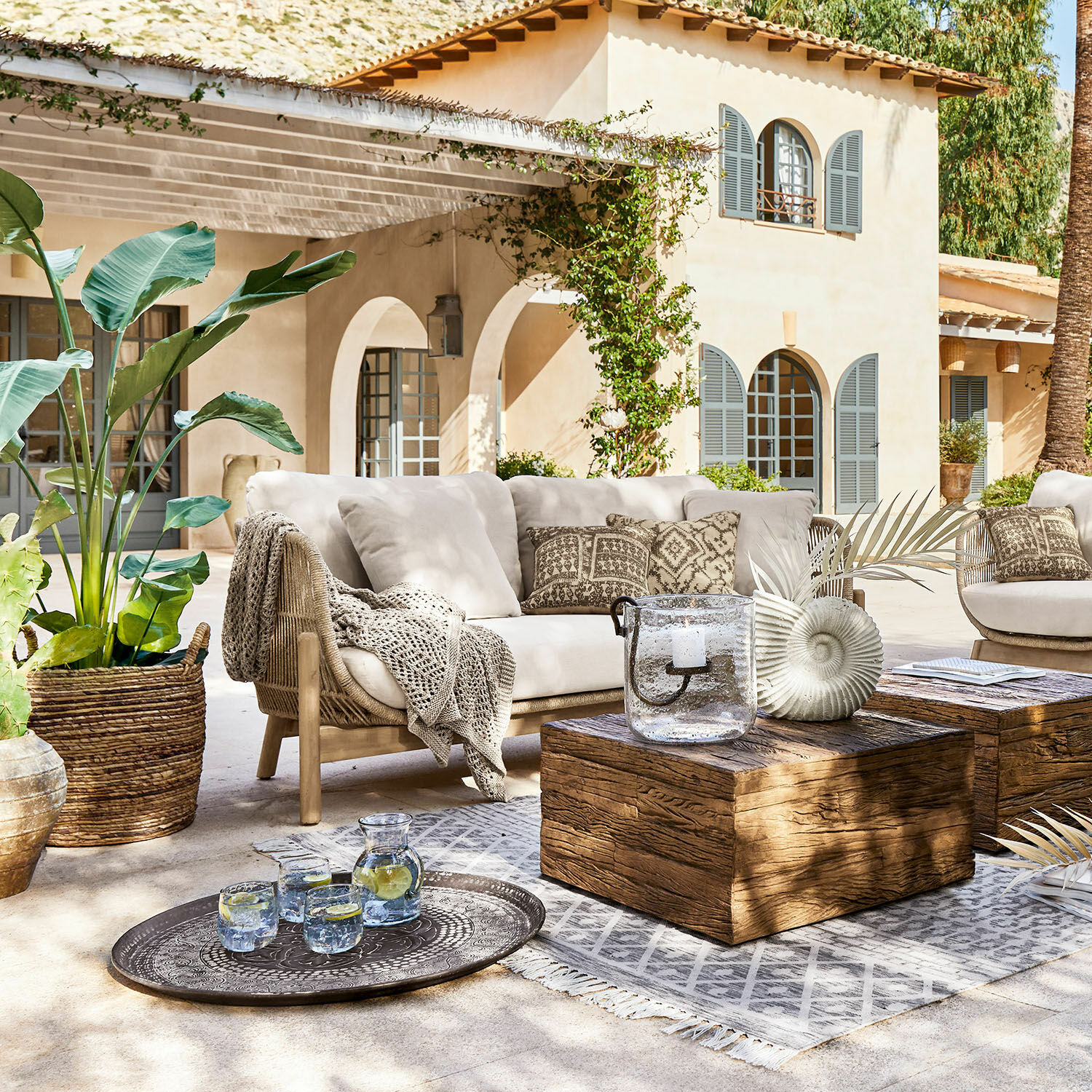 Sofa FSC®-100% Belvidere Zestaw mebli ogrodowych z beżową sofą, drewnianym stolikiem i dekoracjami na tarasie