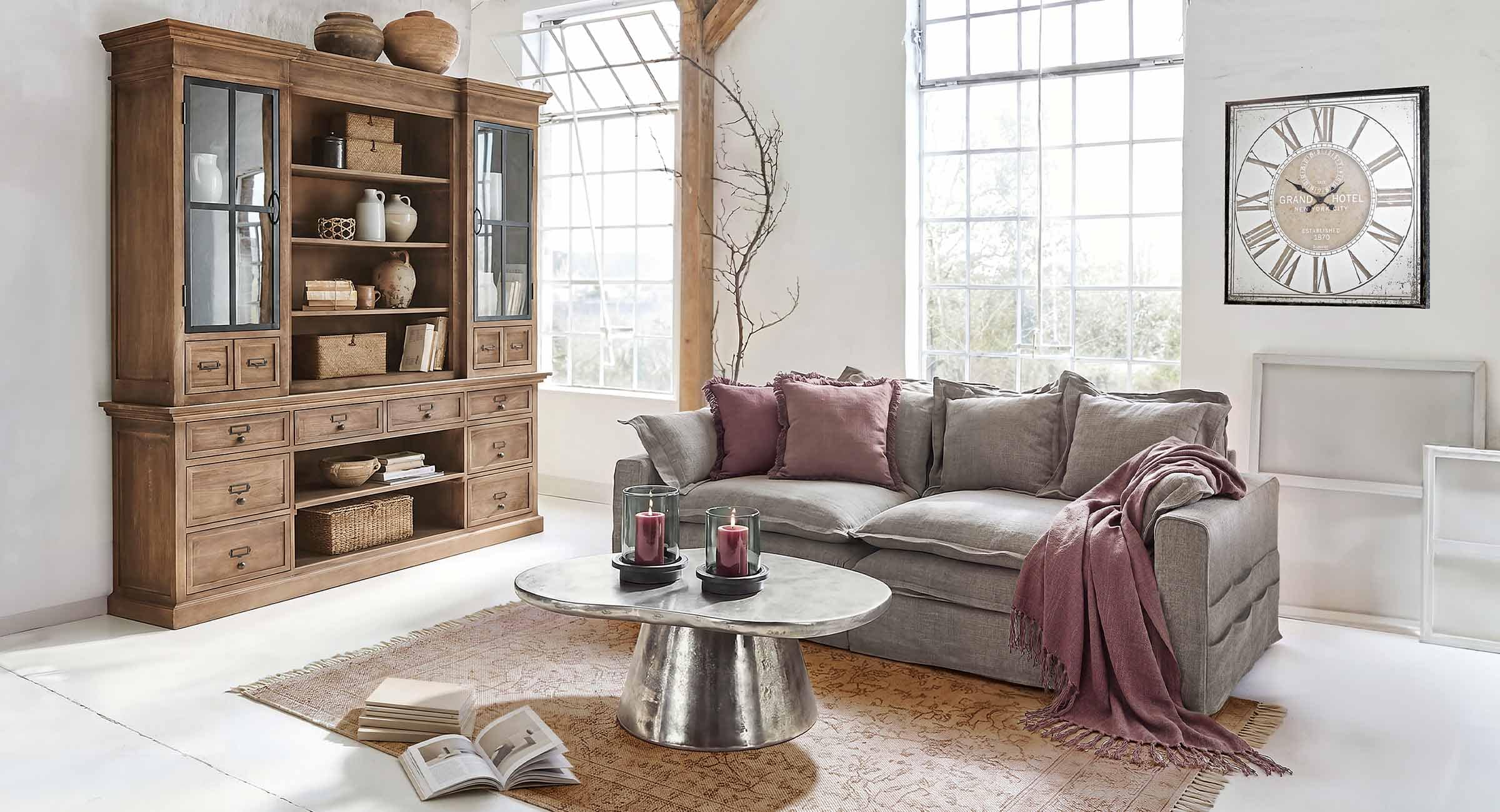 Przytulny salon z szarą sofą, bordowymi poduszkami i drewnianą witryną z dekoracjami w stylu vintage