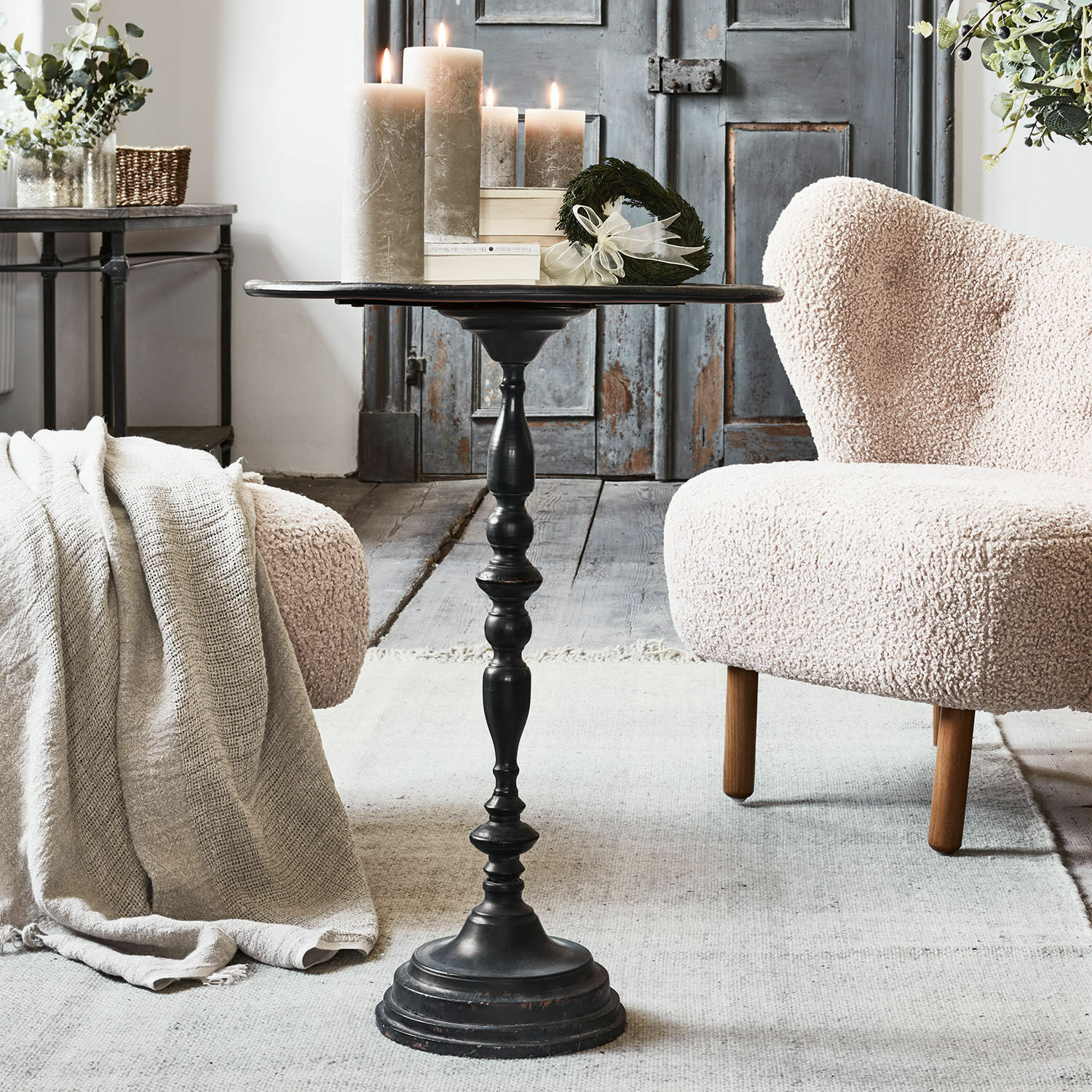 Czarny metalowy stolik boczny z ozdobną podstawą w stylu vintage w przytulnym salonie