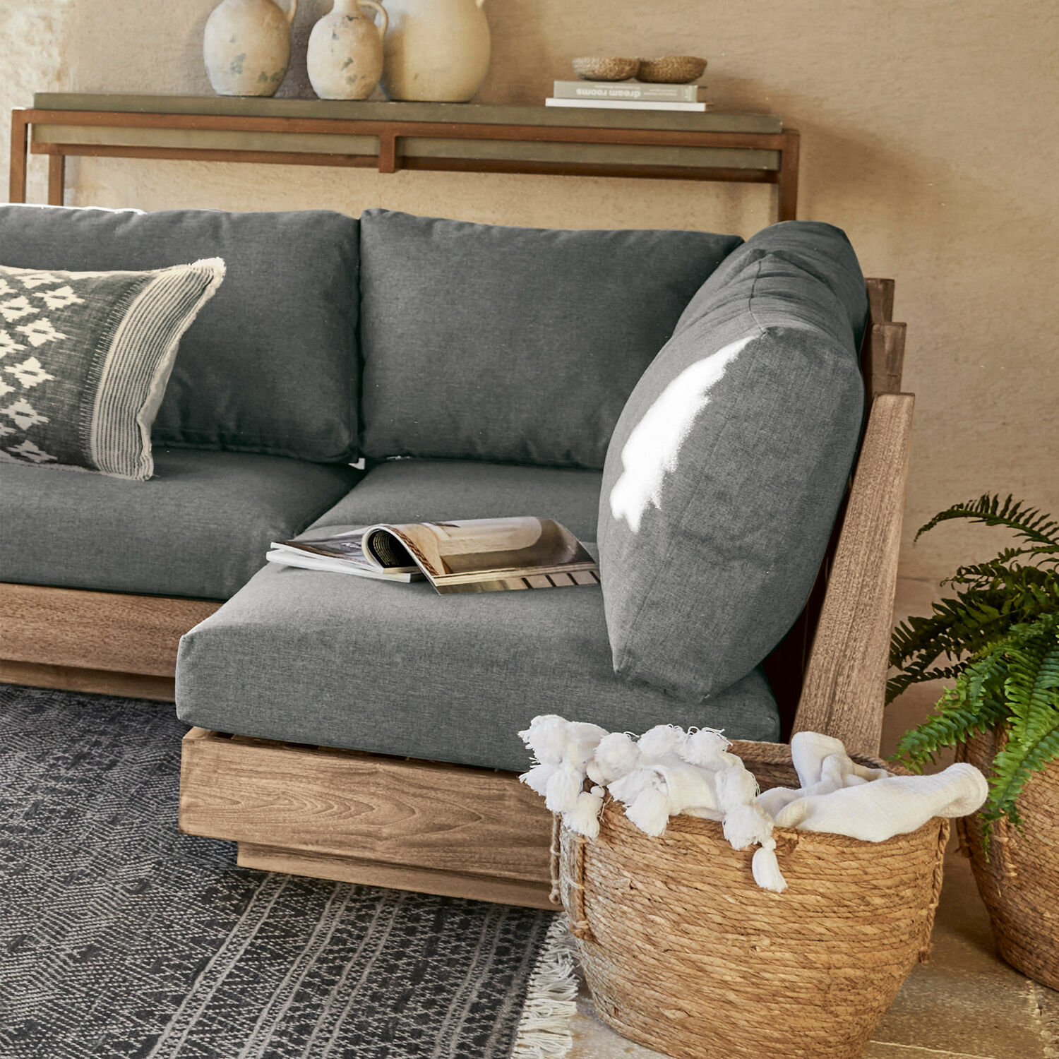 Moduł sofy Courtelevant Szara sofa z drewnianą ramą i miękkimi poduszkami w nowoczesnym salonie z wiklinowym koszem