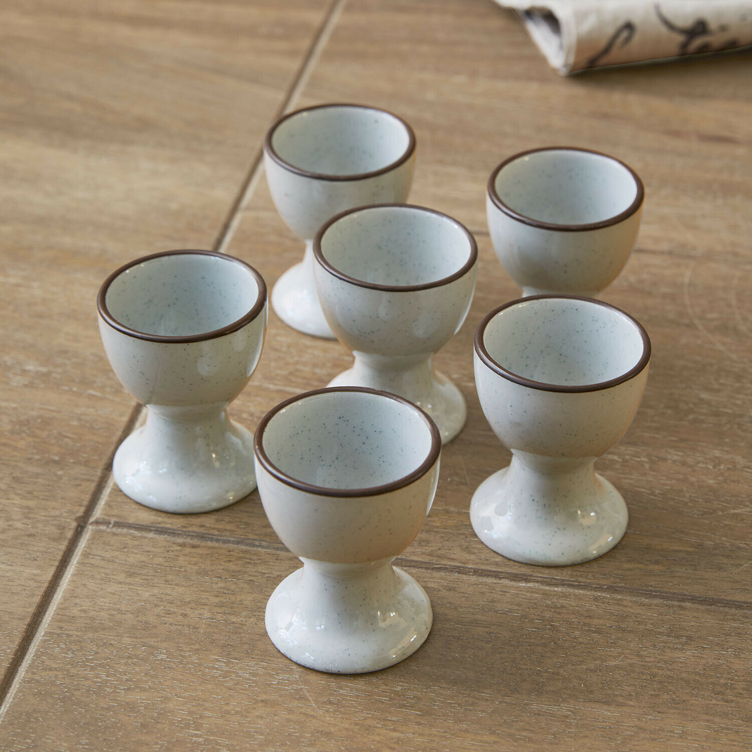 Kieliszek do jajek, zestaw 6 szt. Biarré Zestaw sześciu ceramicznych kieliszków na jajka w kremowym kolorze z brązową obwódką na drewnianym stole