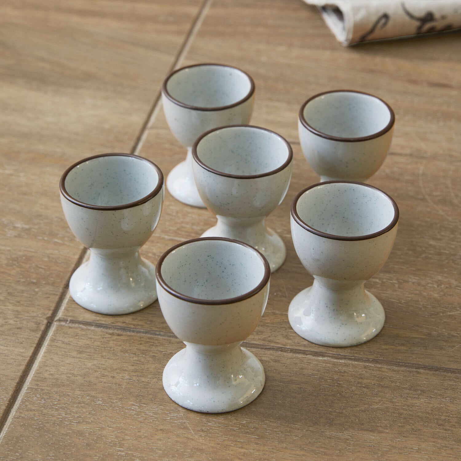 Kieliszek do jajek, zestaw 6 szt. Biarré Zestaw sześciu ceramicznych kieliszków na jajka w kremowym kolorze z brązową obwódką na drewnianym stole