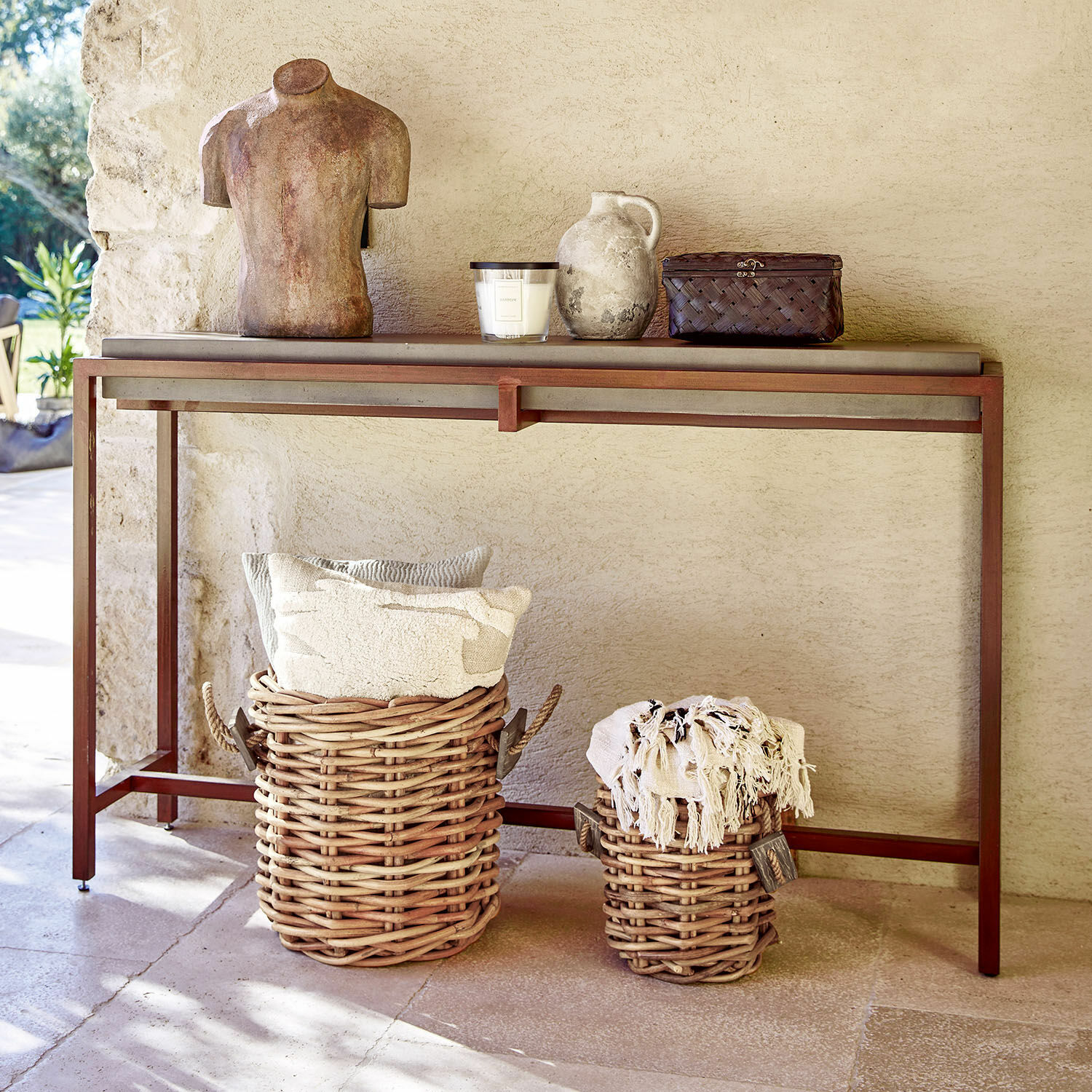 Konsola z metalową ramą i blatem w kolorze rdzy z wiklinowymi koszami i dekoracjami w stylu rustykalnym