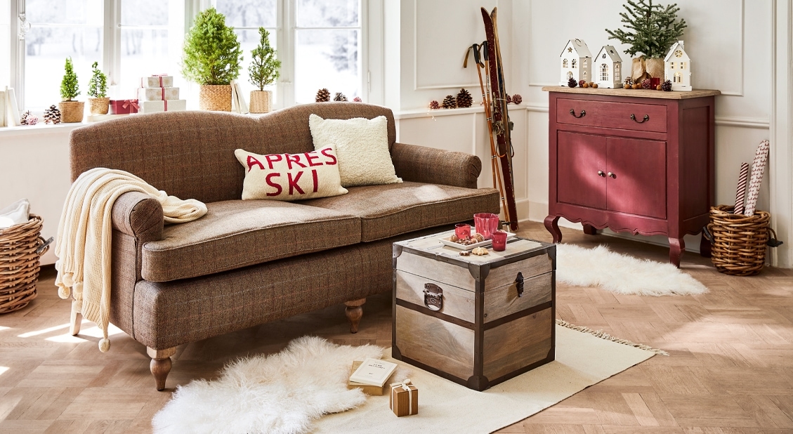 Przytulny salon z brązową sofą, drewnianą skrzynią i czerwonym kredensem w stylu vintage