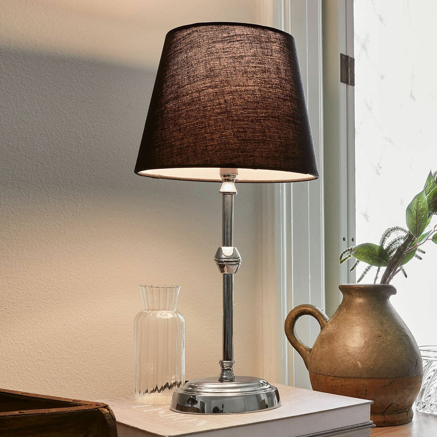 Lampa stołowa Luceau Elegancka lampa stołowa z metalową podstawą i czarnym abażurem na biurku z dekoracją