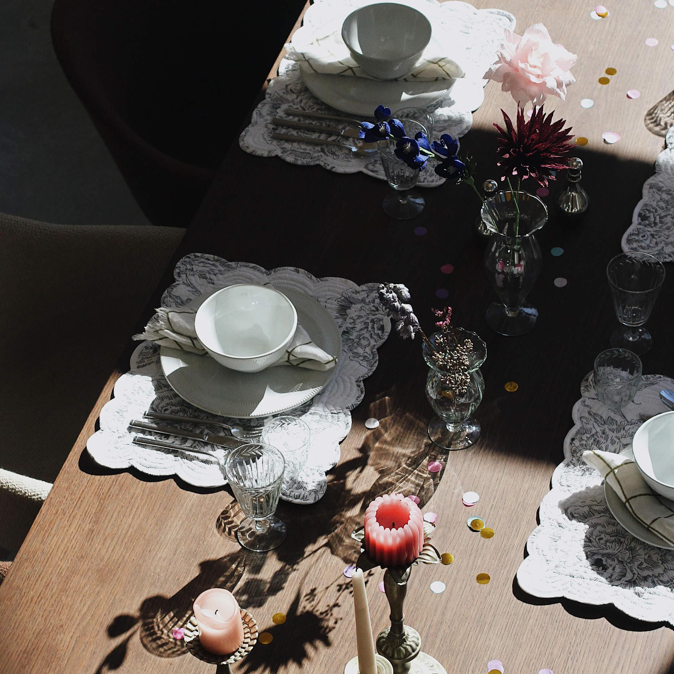 Elegancko nakryty stół z białą porcelaną, szklankami i świecami na drewnianym blacie