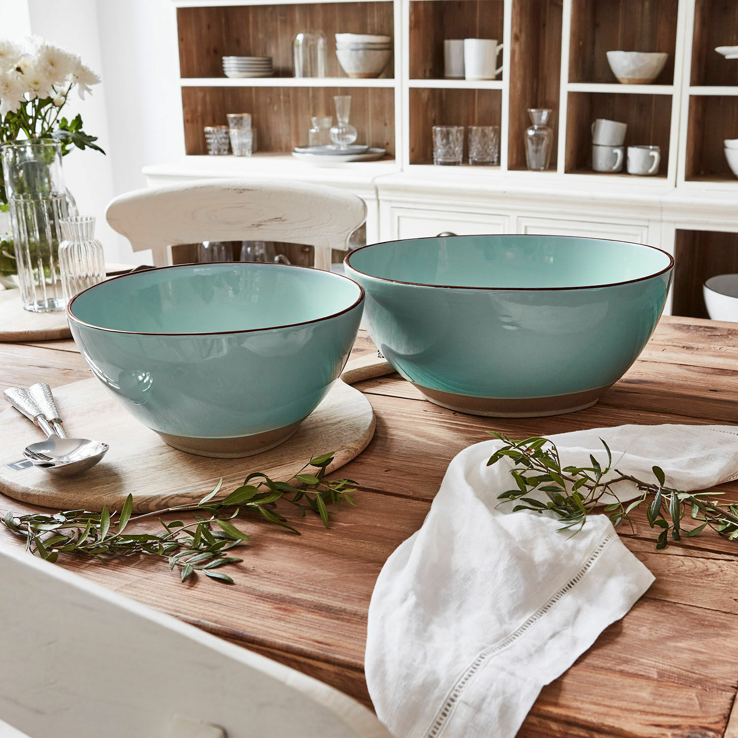 Miska na sałatę, zestaw 2 szt. Biarré Zestaw dwóch ceramicznych mis w turkusowym kolorze na drewnianym stole z dekoracją z zielonych gałązek