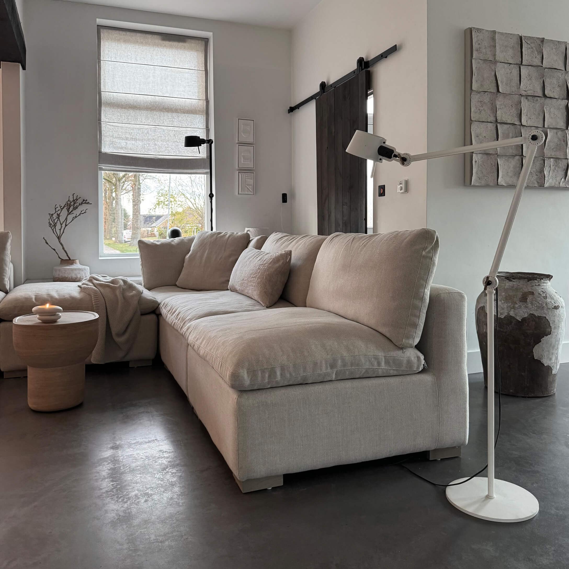 Beżowa sofa narożna z tkaniny w nowoczesnym salonie z lampą stojącą i drewnianym stolikiem