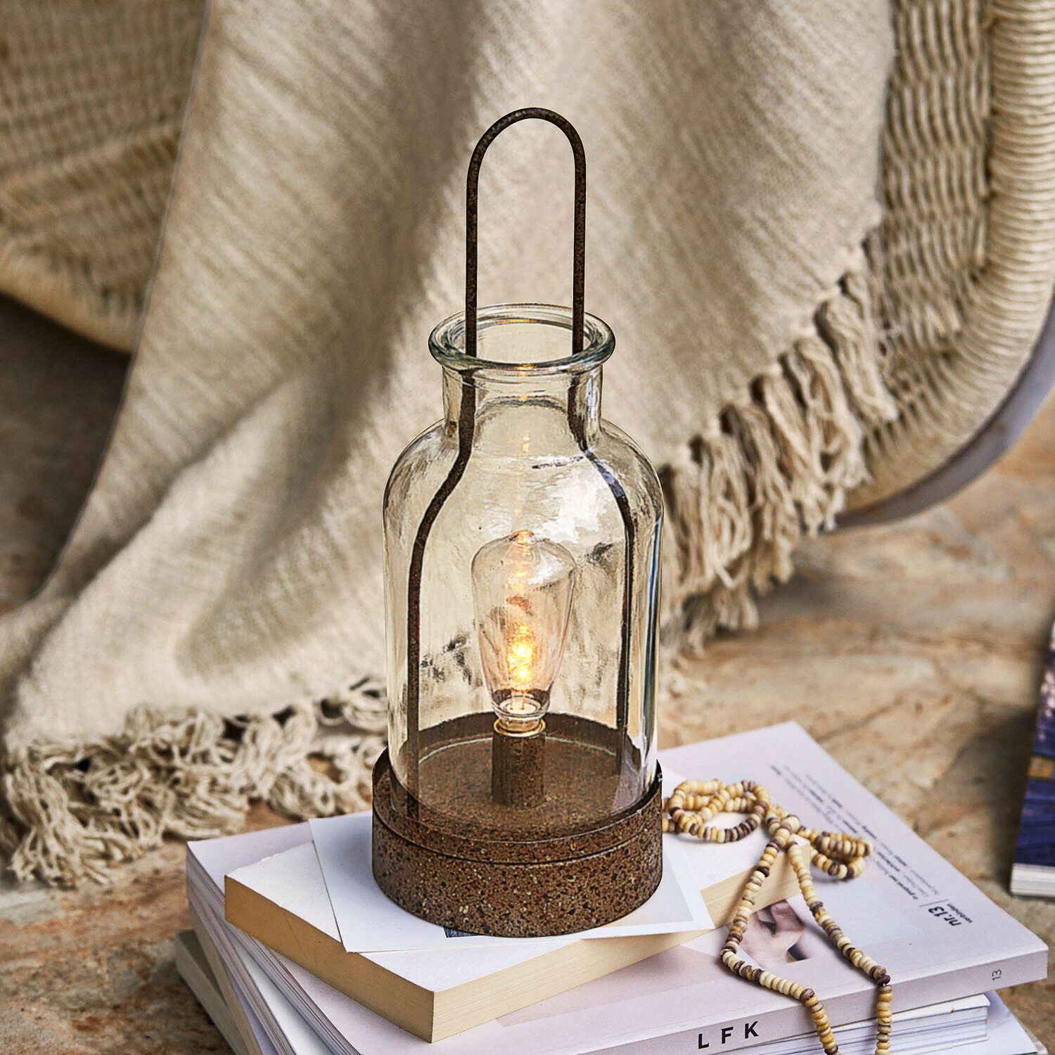 Lampion szklany z metalową podstawą w kolorze rdzy, dekoracyjna lampa stołowa na książkach