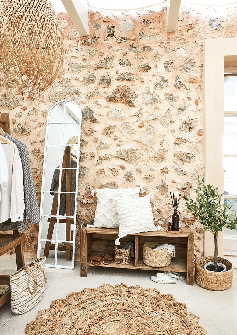 Przytulny kącik z drewnianą ławką, białymi poduszkami i naturalnym dywanem z juty w stylu boho