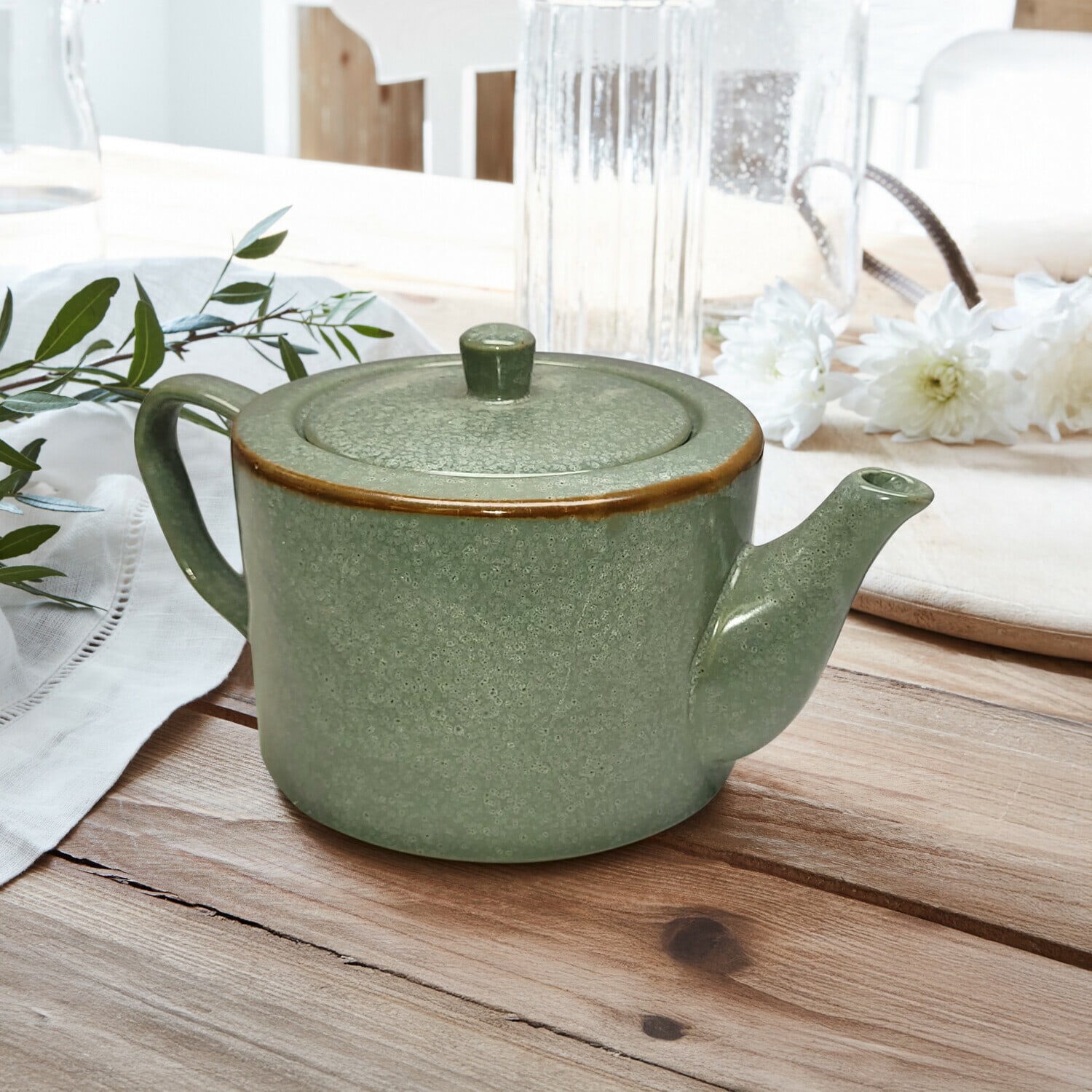 Dzbanek na herbatę Biarré Zielony ceramiczny imbryk z pokrywką i brązowym rantem na drewnianym stole z dekoracją kwiatową