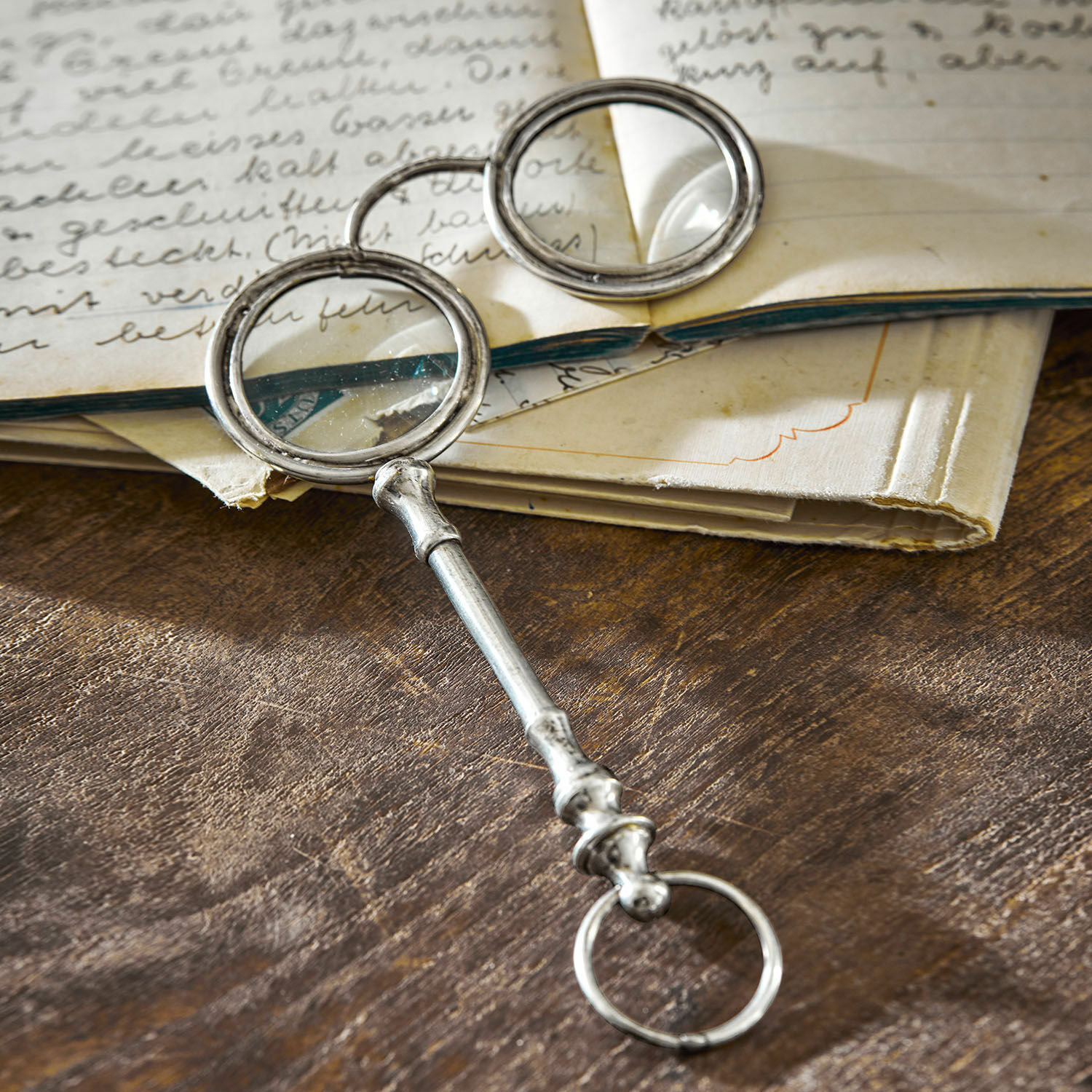 Metalowa lupa z dwoma okrągłymi szkłami na drewnianym stole z otwartą książką