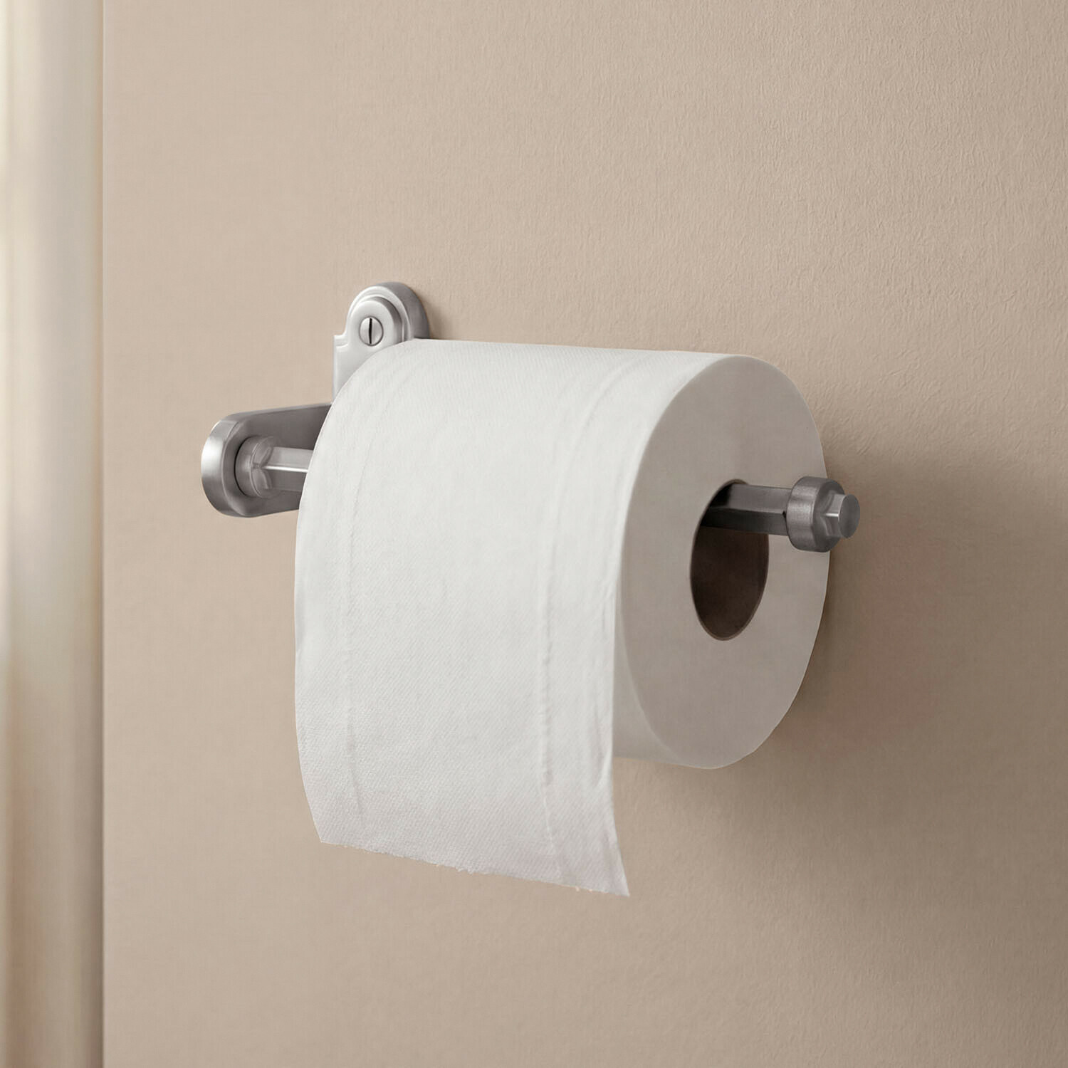Uchwyt na papier toaletowy Virellane Metalowy uchwyt na papier toaletowy w srebrnym kolorze zamontowany na beżowej ścianie