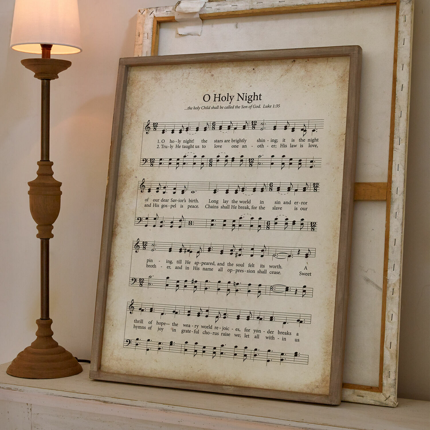 Obraz Holy Night Obraz z nutami i tekstem kolędy O Holy Night w drewnianej ramie na tle lampy i ściany
