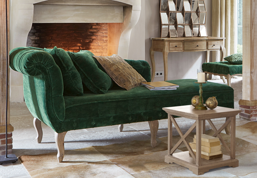 Klasyczna zielona aksamitna sofa z drewnianymi nogami w eleganckim salonie z kominkiem