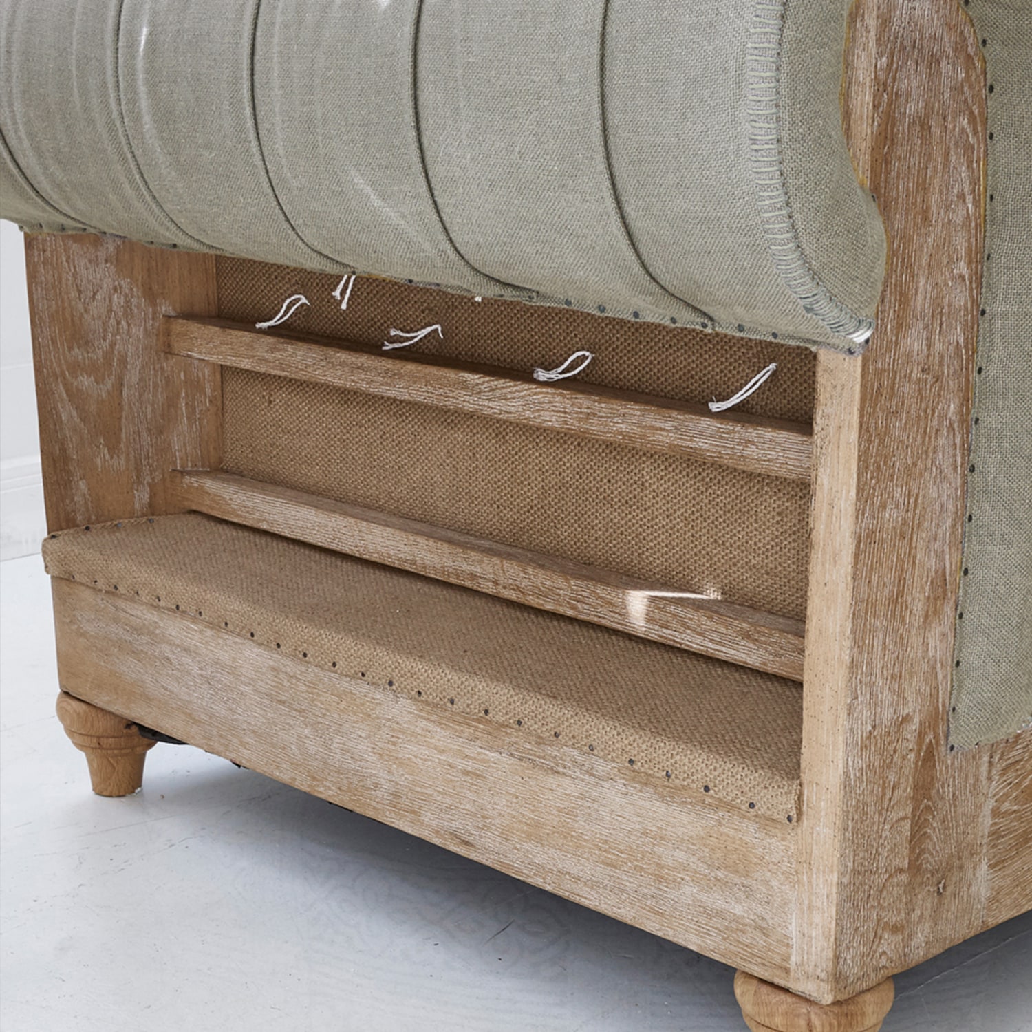 Sofa z jasnego drewna i beżowej tkaniny z widoczną konstrukcją i detalami wykończenia mebla