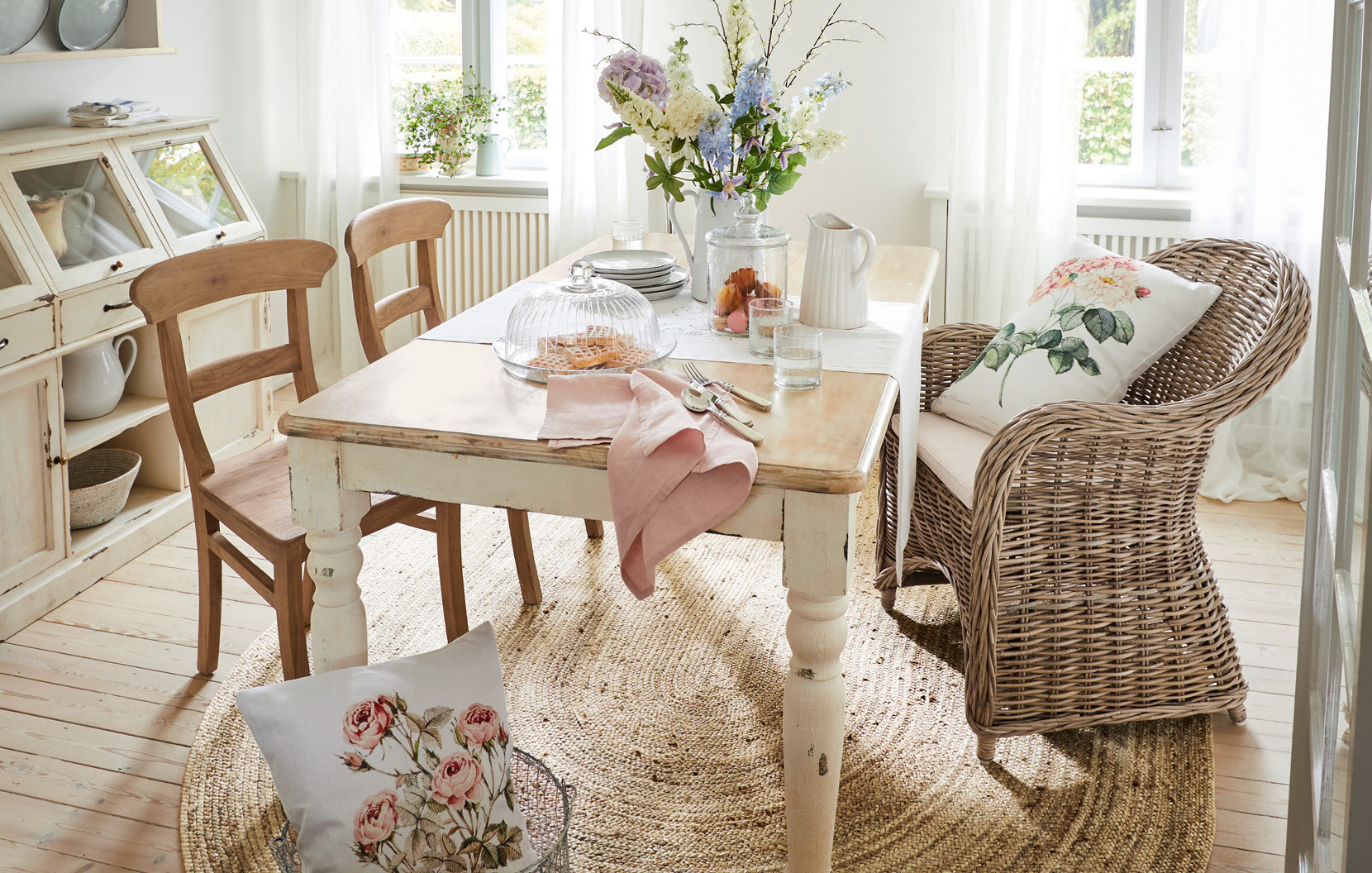 Jadalnia w stylu shabby chic z drewnianym stołem, wiklinowym fotelem i kwiatową dekoracją