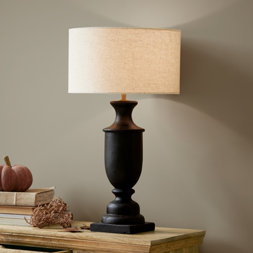 Czarna ceramiczna lampa stołowa z beżowym abażurem na drewnianym stole, dekoracja wnętrza