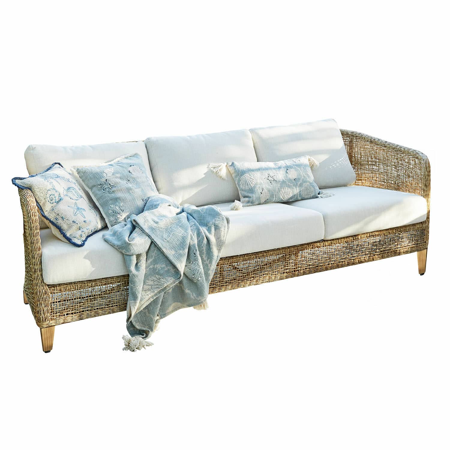 Sofa Clarivaux Sofa z rattanu z kremowymi poduszkami i niebieskim kocem z motywem morskim do salonu