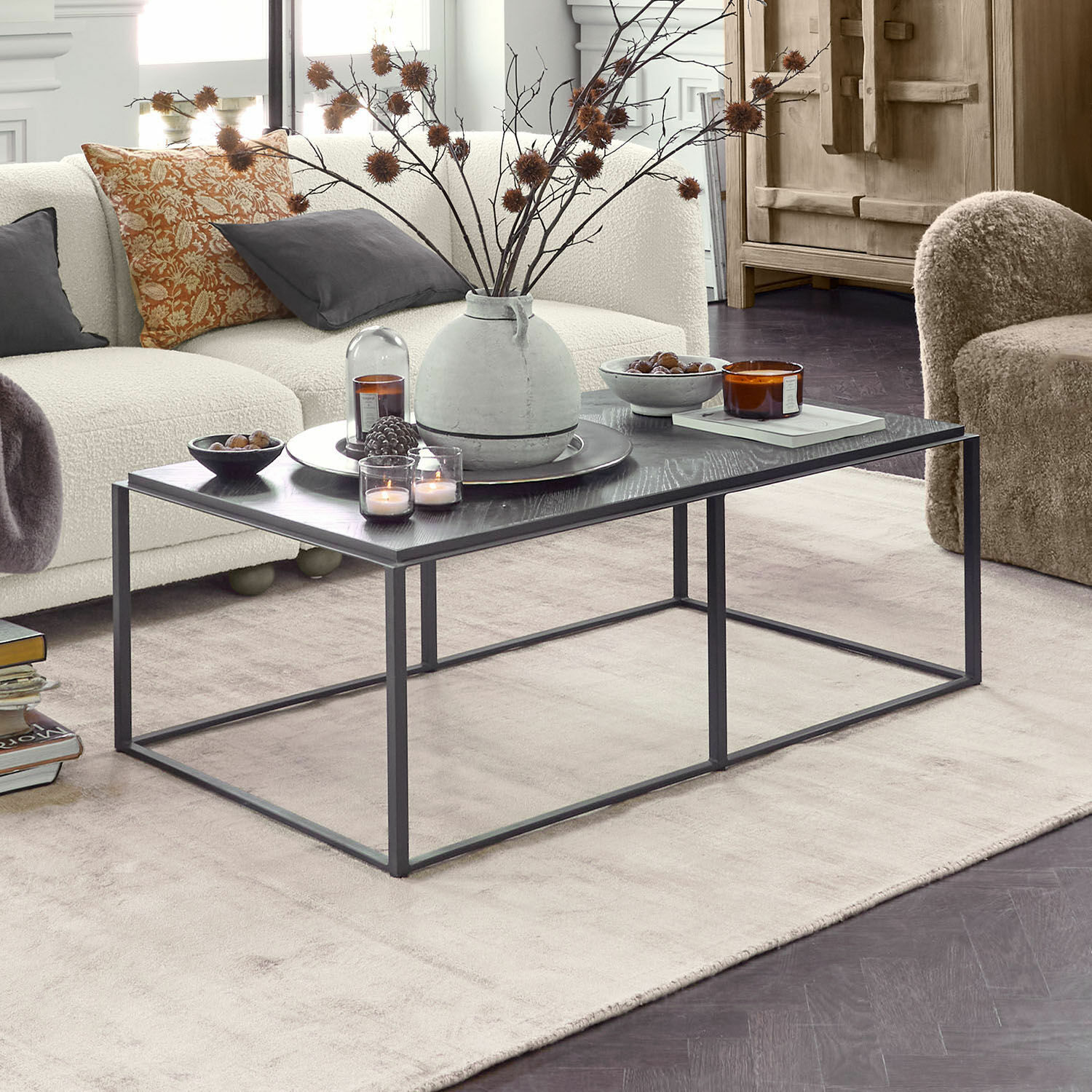 Nowoczesny czarny stolik kawowy z metalową ramą i dekoracjami w jasnym salonie z beżową sofą