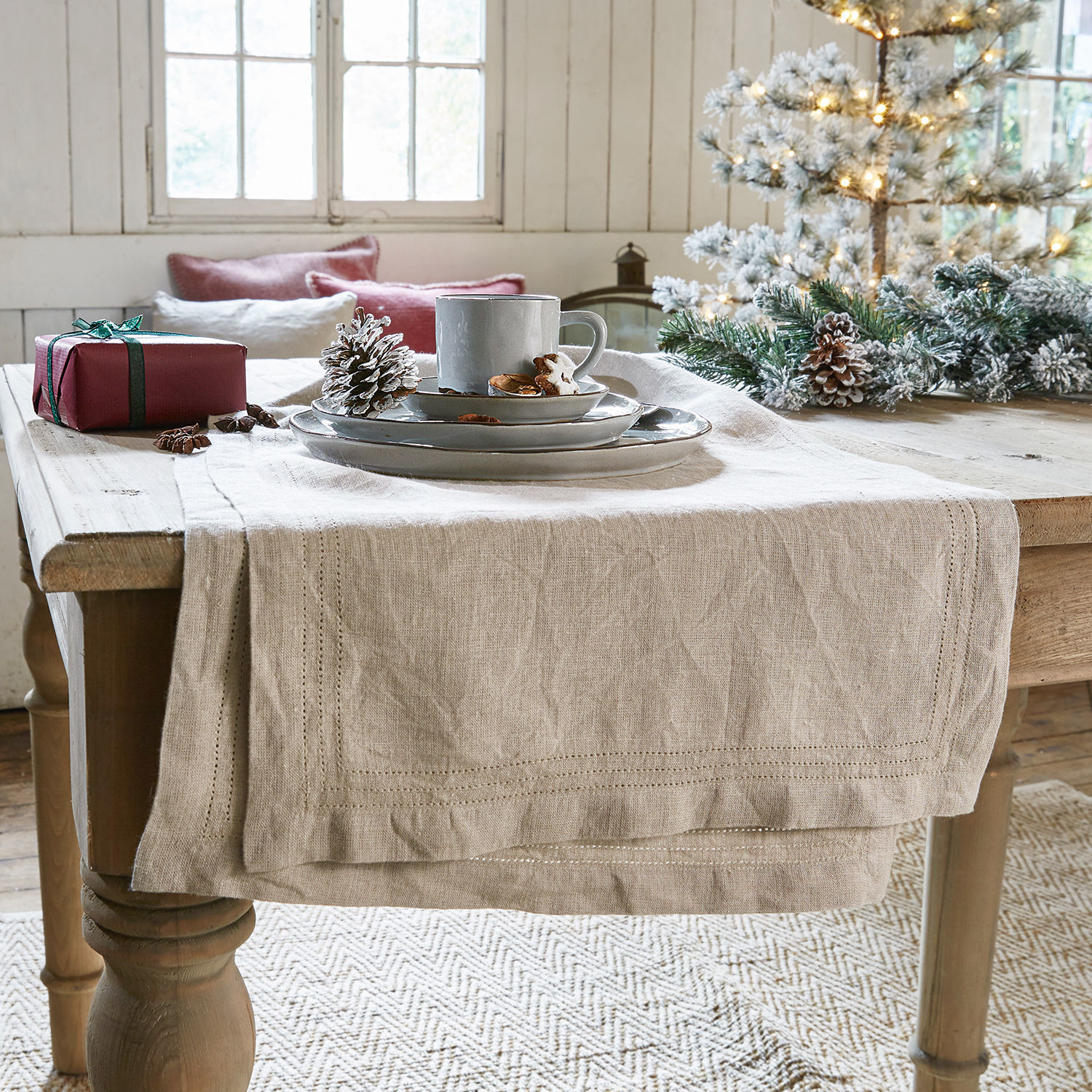Bieżnik Brion Lniany beżowy bieżnik na drewnianym stole z dekoracjami świątecznymi i zastawą stołową