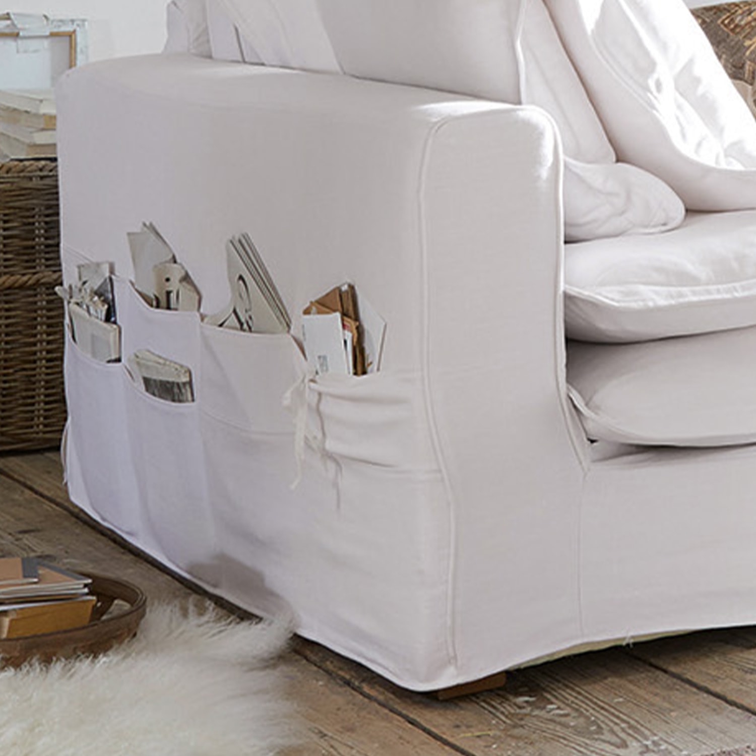 Biała bawełniana sofa z praktycznymi kieszeniami na magazyny i książki w salonie