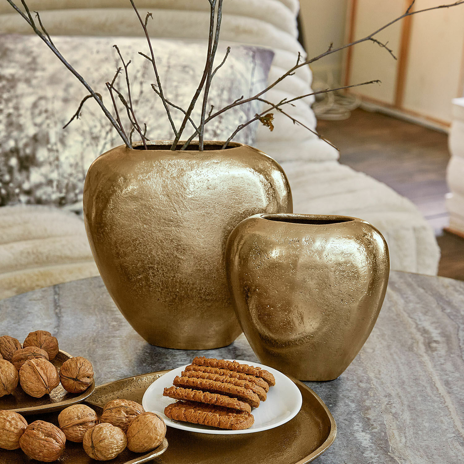 Wazon, zestaw 2 szt. Cezelle Zestaw dwóch złotych ceramicznych wazonów na stole z orzechami i ciastkami w salonie