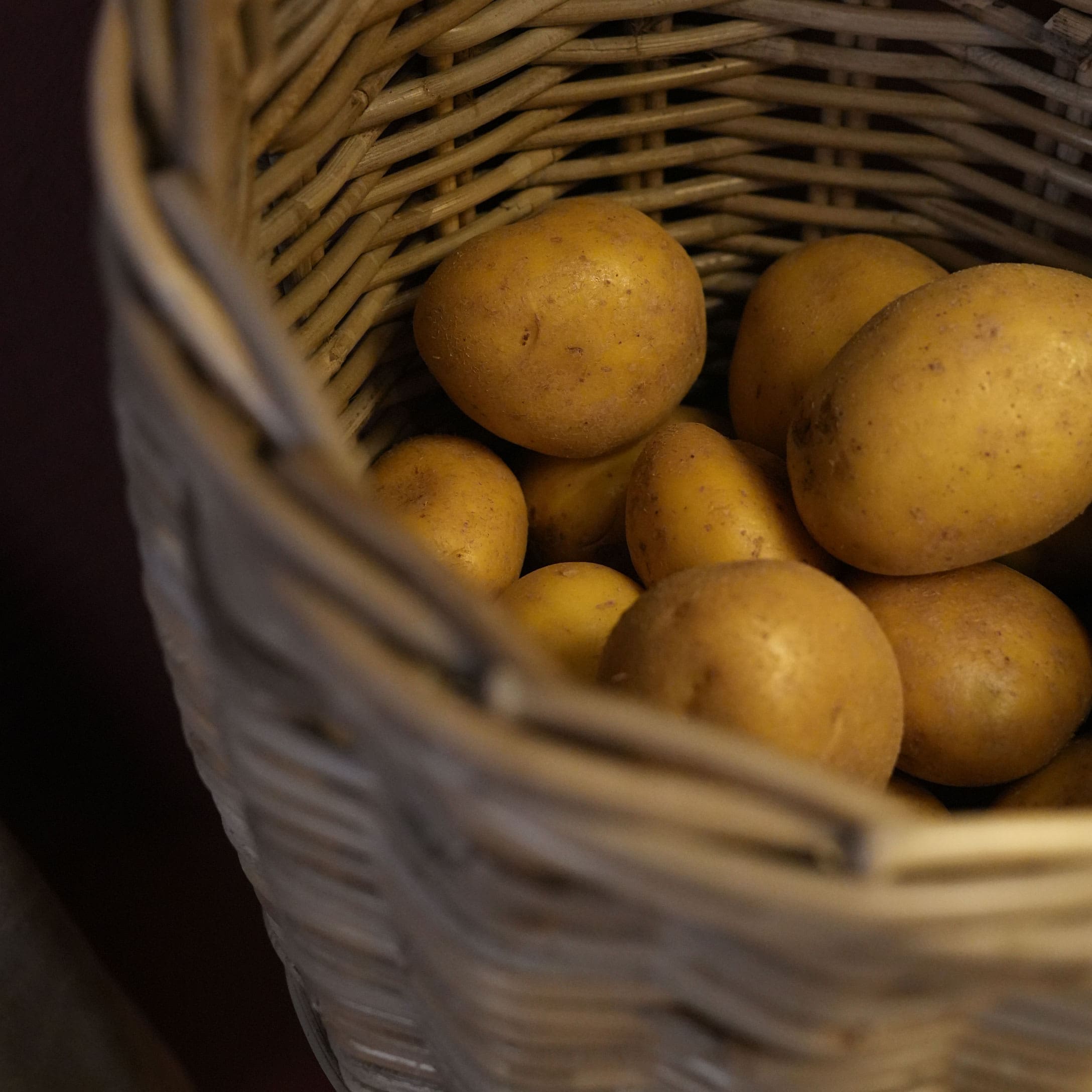 Ziemniaki w wiklinowym koszu o naturalnym kolorze, świeże warzywa do kuchni