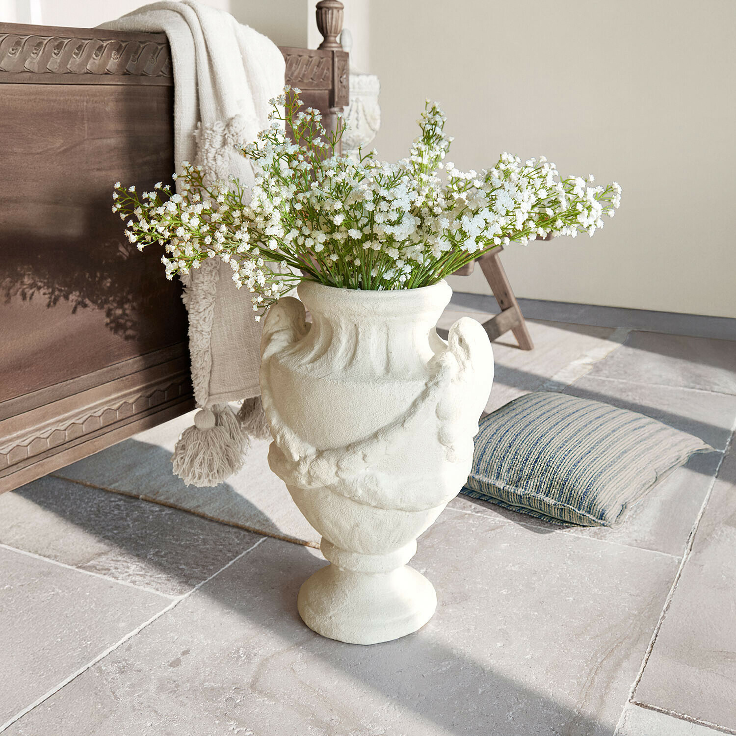 Osłonka doniczki Chaverny Biała ceramiczna waza z dekoracyjnym wzorem i białymi kwiatami na podłodze z kamienia