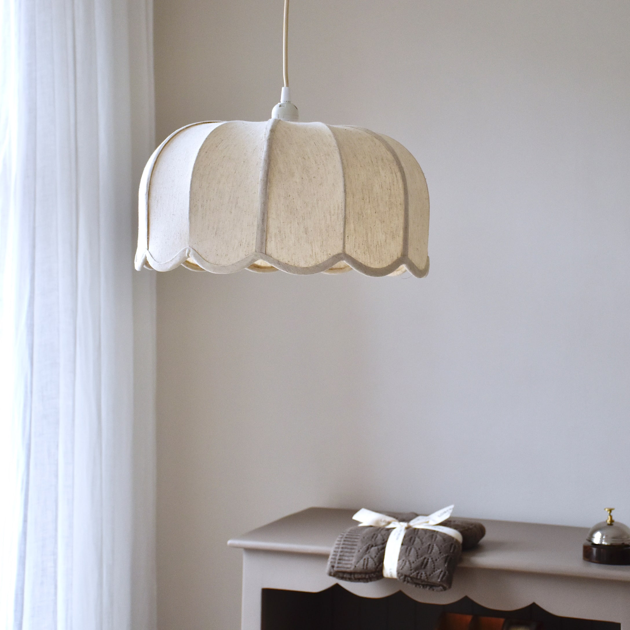 Wisząca lampa z tkaniny w kremowym kolorze o falistym kształcie, delikatne oświetlenie wnętrza
