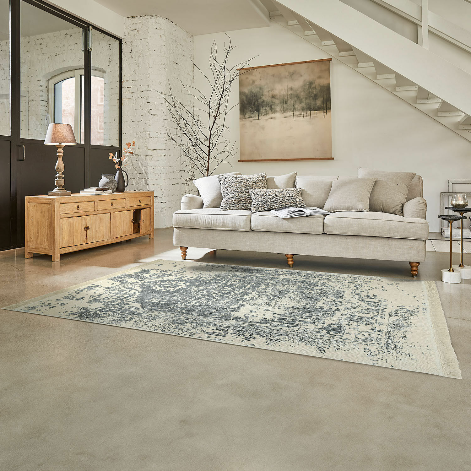 Dywan Lortet Beżowa sofa z poduszkami i drewniana komoda w jasnym salonie z dywanem vintage