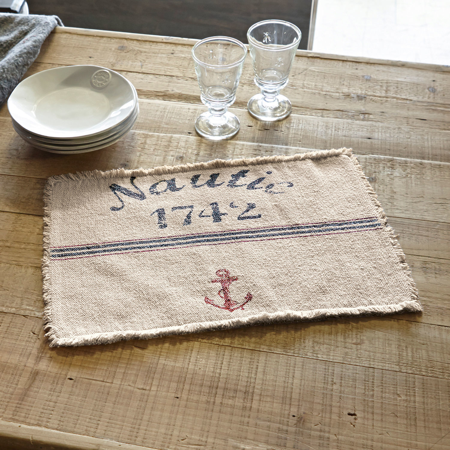 Podkładka, zestaw 2 szt. Nautic Beżowa bawełniana podkładka z nadrukiem kotwicy i napisem Nautic 1742 na drewnianym stole