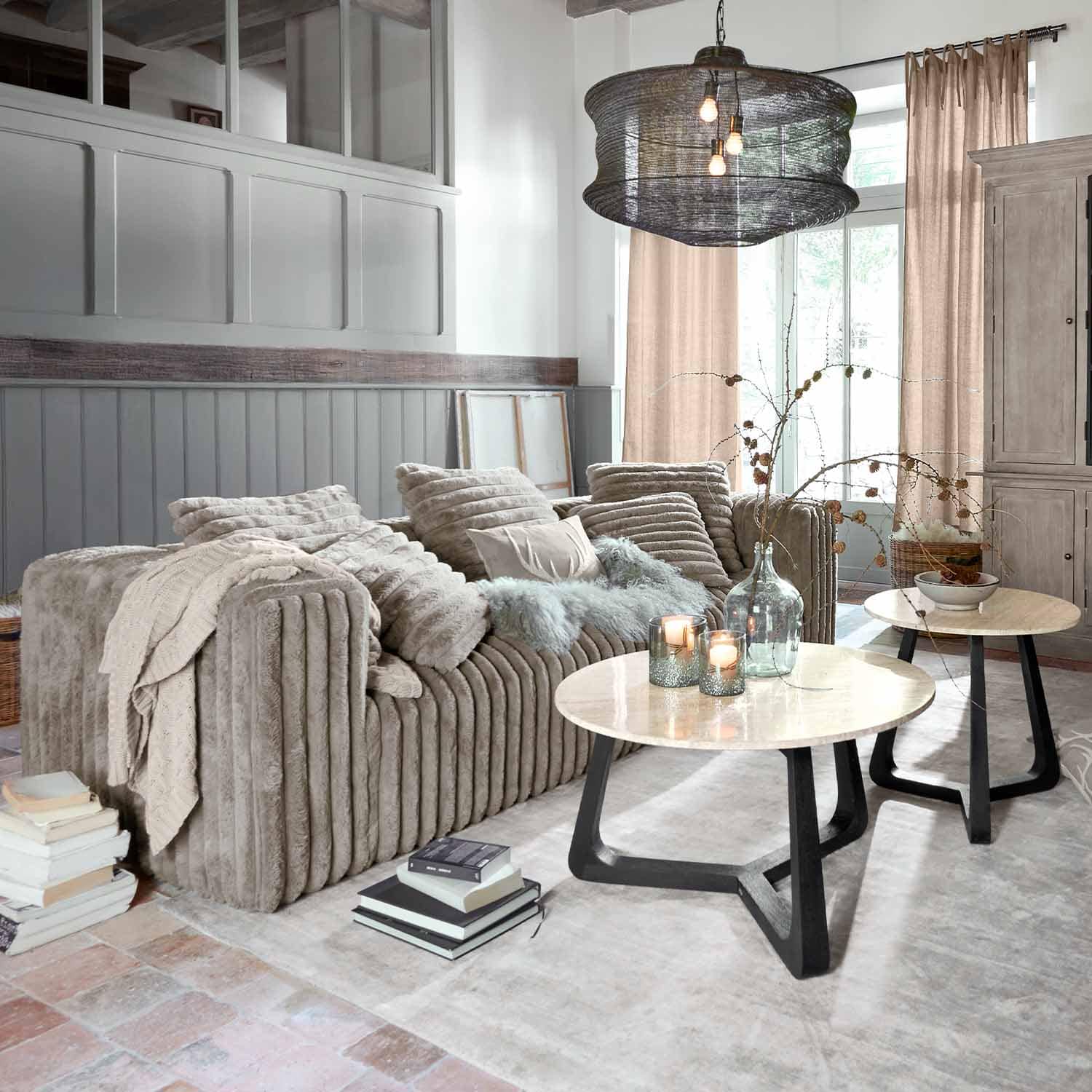 Przytulna sofa z miękkiego beżowego materiału w nowoczesnym salonie z dwoma stolikami kawowymi