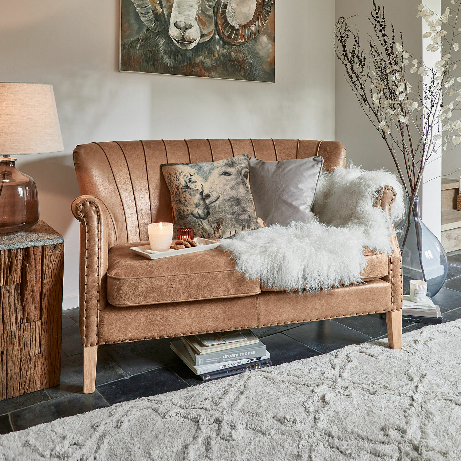 Sofa Brookfield Brązowa sofa z miękkiego materiału z dekoracyjnymi poduszkami i białym futrzanym kocem w salonie
